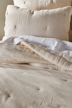 an unmade bed with white sheets and pillows