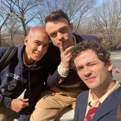 three young men posing for the camera in front of some trees and one has his hand on his head