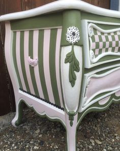 a green and white striped dresser sitting on top of gravel