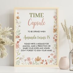 a white framed sign sitting on top of a table next to vases and flowers