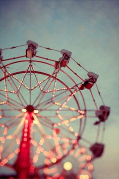 a ferris wheel is lit up at night time with the sky in the back ground