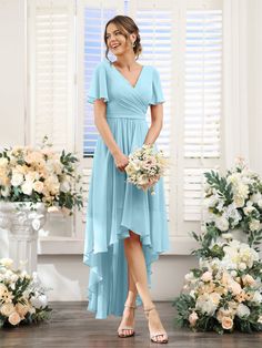 a woman standing in front of flowers wearing a blue bridesmaid dress with short sleeves