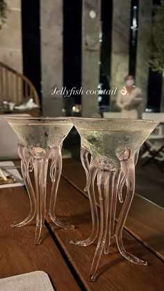 two glass vases sitting on top of a wooden table