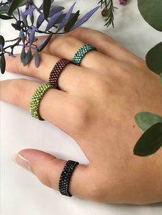 a person's hand with two different bracelets on their fingers and one is holding a plant