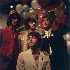 a group of men standing next to each other in front of balloons