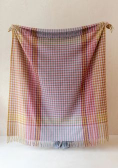 a pink and yellow checkered blanket with tassels hanging from it's end