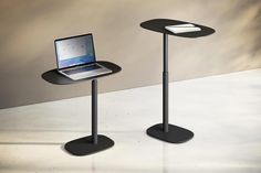 a laptop computer sitting on top of a black table next to a stand with a keyboard