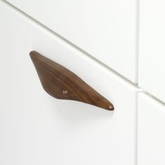 a wooden drawer handle on a white cabinet