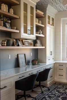 a home office with white cabinets and black chairs