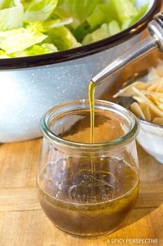 the dressing is being poured into a glass jar next to a salad in a bowl