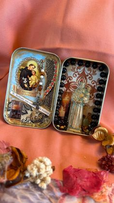 two tins filled with different items sitting on top of a pink cloth covered bed