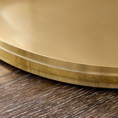 a close up of a gold plate on a wooden table with wood grained flooring