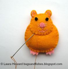 a mouse pin cushion with a needle in the shape of a rat on it's back