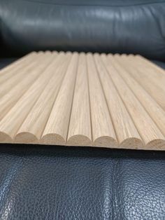 a close up of a wooden board on a black leather couch with a blue leather chair in the background