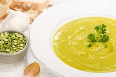 a white bowl filled with soup next to some bread and an onion on a table