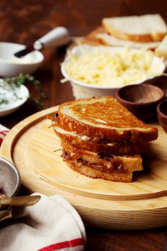 there is a sandwich on a wooden plate with other dishes in the backgroud