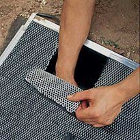 a person holding a knife over a metal grate on top of a dirt ground