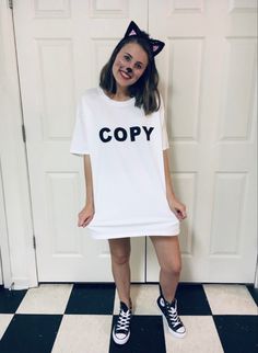 a woman wearing a white t - shirt with the word copy printed on it, standing in front of a black and white checkered floor