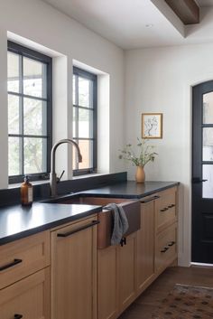 a kitchen with wooden cabinets and black counter tops, along with a large window over the sink