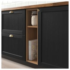 a kitchen cabinet with black doors and drawers