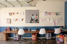 an office with two desks and chairs in front of a wall hanging pictures on the wall