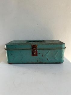 an old green metal box sitting on top of a white counter next to a wall