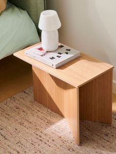 a wooden table with a book on it and a white vase sitting on top of it