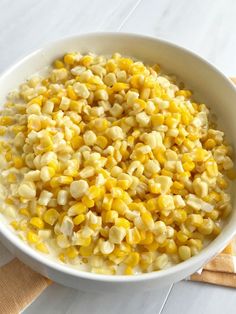 a white bowl filled with corn on top of a table