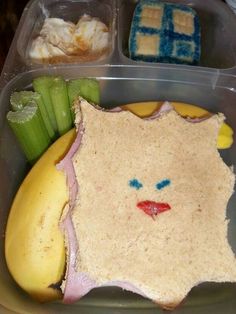 a plastic container with some food in it and a face made out of bread on the side