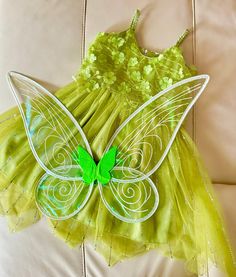 a green fairy dress sitting on top of a white couch