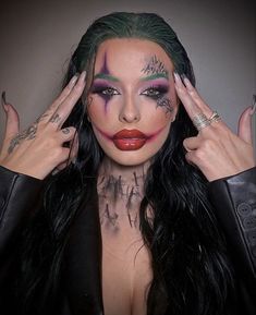 a woman with green hair and makeup is holding her hands up to her face while wearing black leather jacket