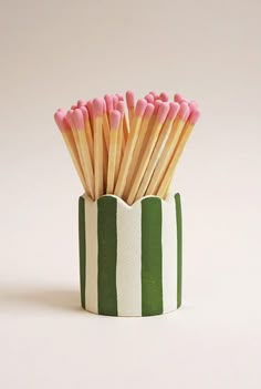 a cup that has some pink and green matchesticks sticking out of it's sides