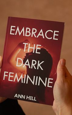 the book embrace the dark feminine by ann hill is held up in front of a woman's face