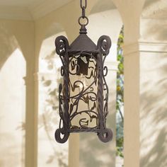 an outdoor light hanging from a chain on the outside of a house with columns and pillars