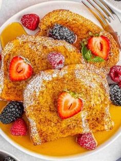 french toast topped with berries and powdered sugar on a plate next to silverware