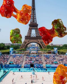 there are many gummy bears in front of the eiffel tower with people playing volleyball