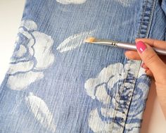 a woman's hand is holding a brush near the pocket of her jean jacket