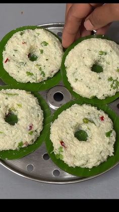 four green plates filled with food sitting on top of a table next to a person's hand