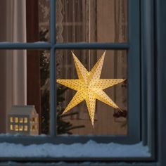 a lighted star hanging from the side of a window