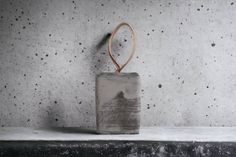 a concrete container with a wooden handle on top of a shelf in front of a cement wall