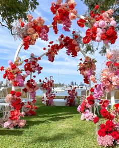 an outdoor wedding ceremony with flowers on the arch and chairs in the grass behind it