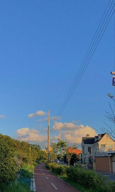 a street sign on the side of a road with power lines above it and houses in the background