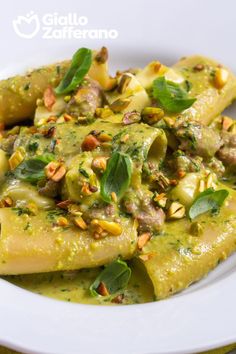 a white plate topped with ravioli covered in pesto and pine nut toppings