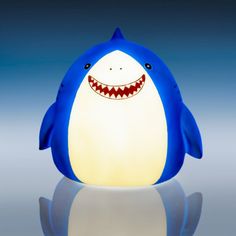 a blue and white shark lamp sitting on top of a reflective surface with its mouth open