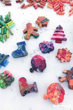 there are many different colored clay shapes on the snow covered ground with crayons