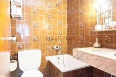 a bathroom with a toilet, sink and bathtub next to a mirror on the wall