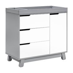 a white dresser with three drawers and two black handles on the bottom, against a white background