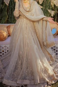 a woman in a wedding dress sitting on a bench with an umbrella over her head