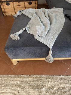 a bed with a blanket on top of it next to a wooden dresser and drawers