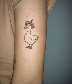 a woman's arm with a small tattoo of a duck and flowers on it